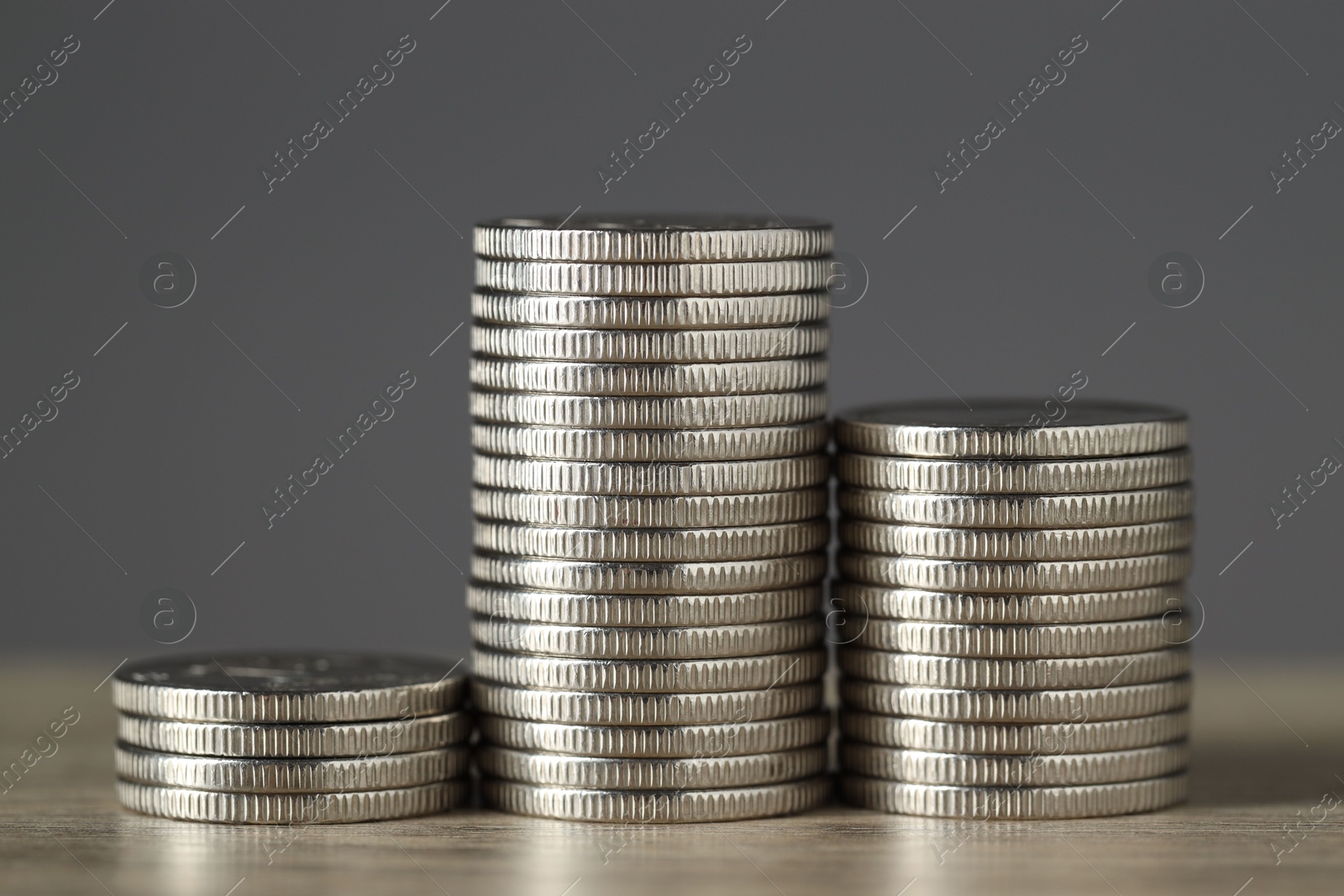 Photo of Stacked coins on wooden table against grey background, closeup. Salary concept