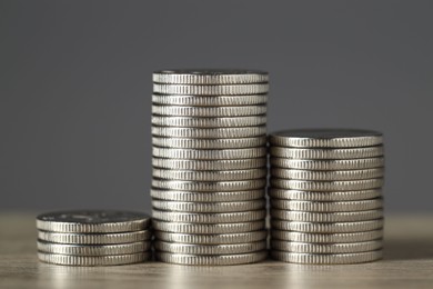 Photo of Stacked coins on wooden table against grey background, closeup. Salary concept