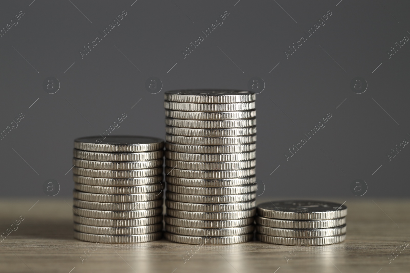 Photo of Stacked coins on wooden table against grey background, closeup. Salary concept