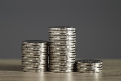 Photo of Stacked coins on wooden table against grey background, closeup. Salary concept