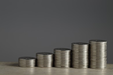 Photo of Stacked coins on wooden table against grey background, closeup with space for text. Salary concept