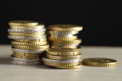 Photo of Stacked coins on wooden table against black background, closeup. Salary concept