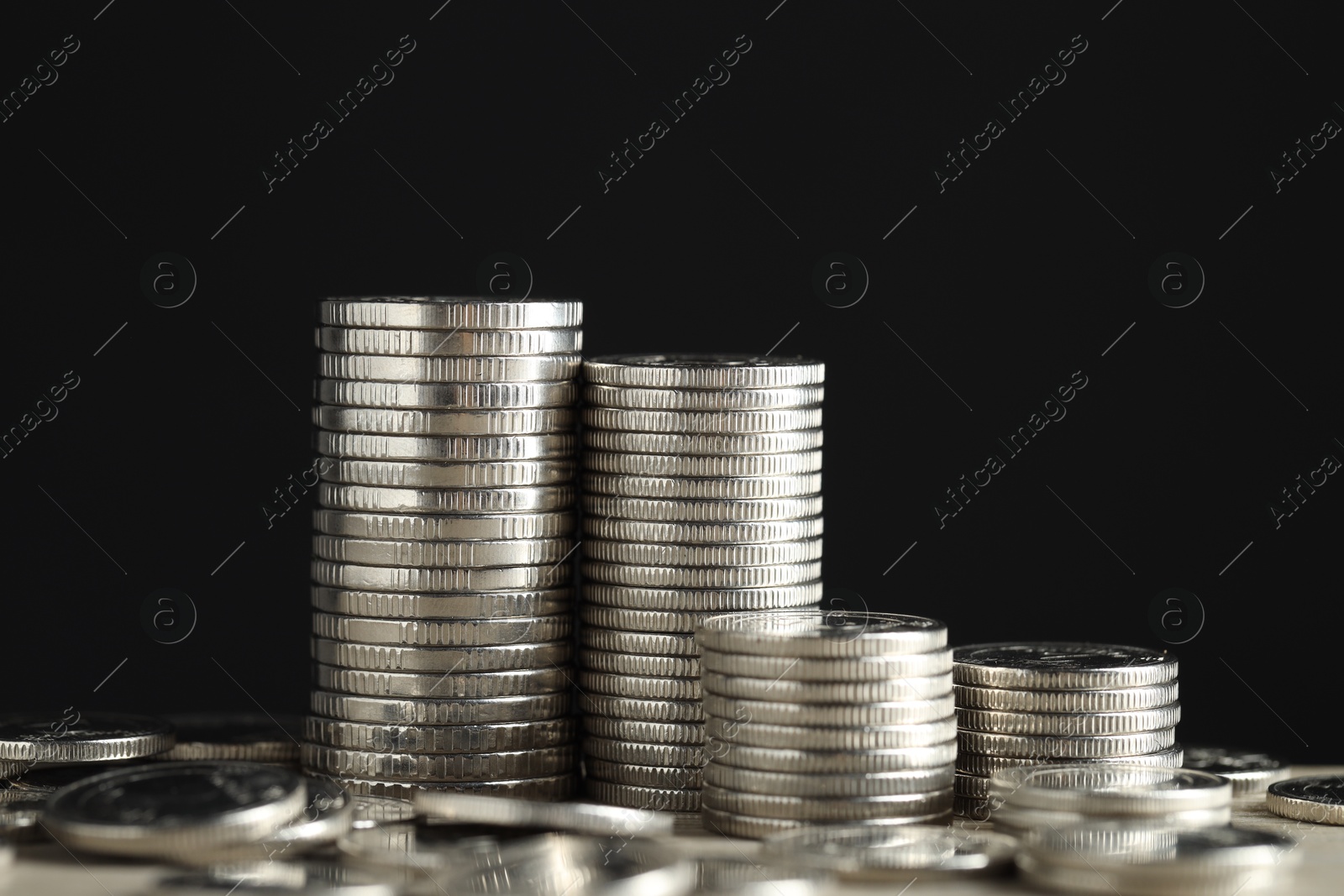 Photo of Stacked coins on table against black background, closeup. Salary concept