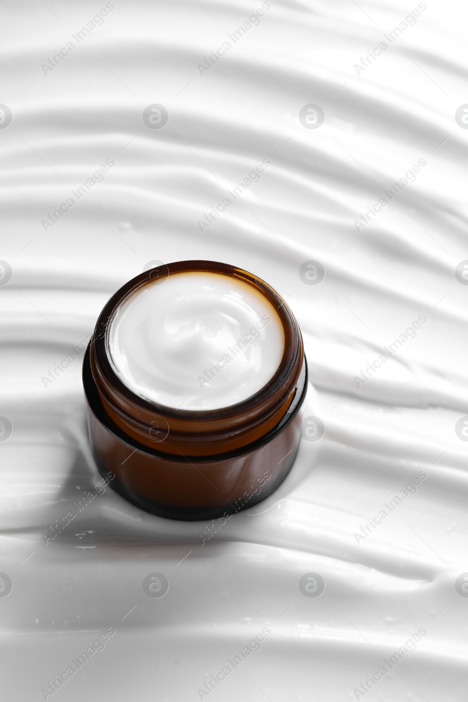 Photo of Face cream in jar on cosmetic product, closeup