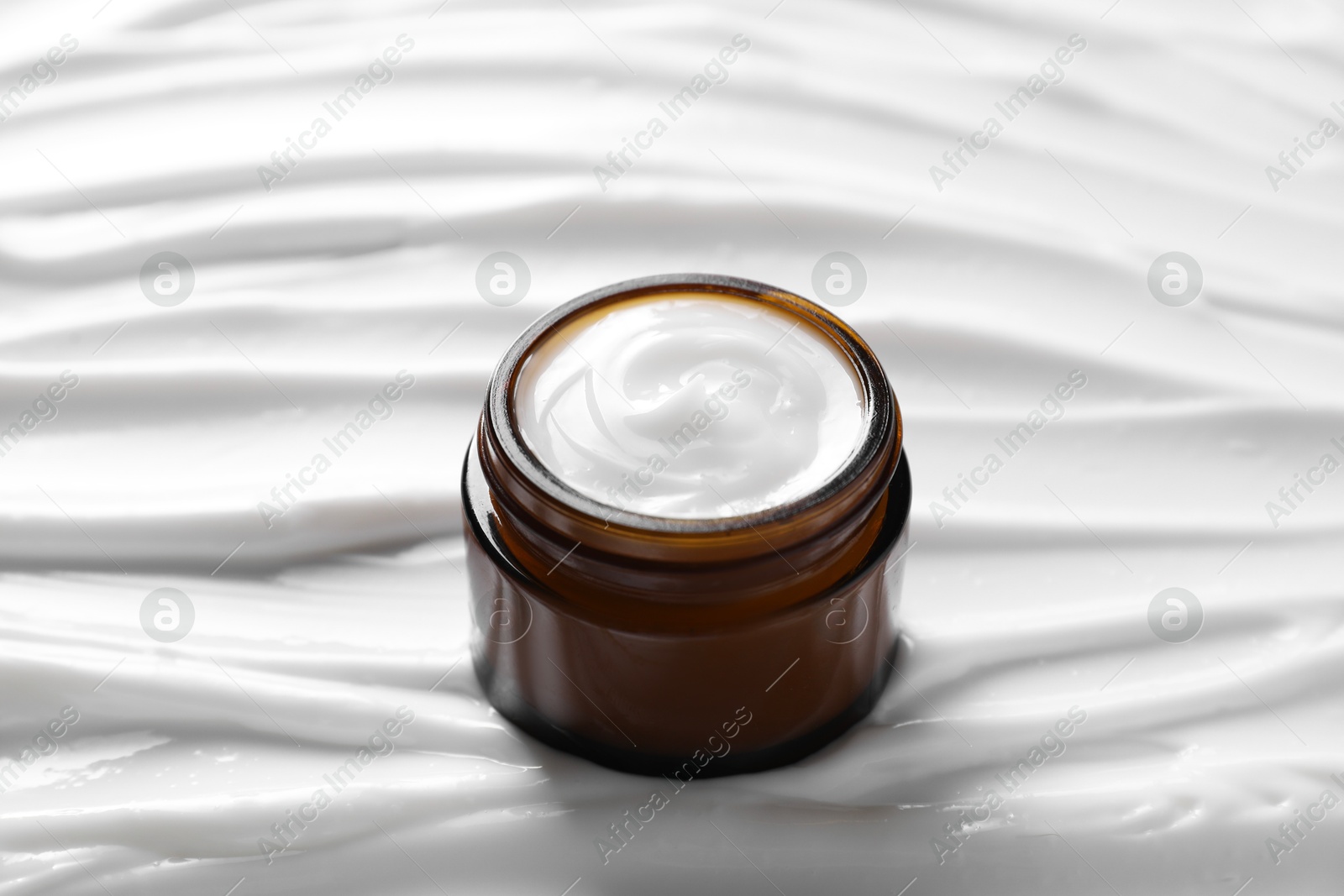 Photo of Face cream in jar on cosmetic product, closeup