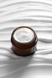 Photo of Face cream in jar on cosmetic product, closeup