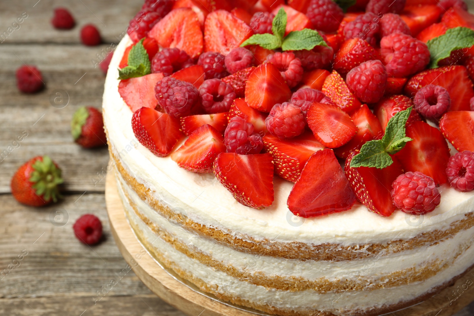 Photo of Tasty sponge cake with fresh berries and mint on wooden table, closeup