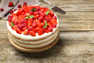 Photo of Tasty sponge cake with fresh berries and mint on wooden table, space for text