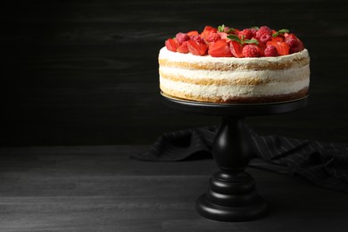 Photo of Tasty sponge cake with fresh berries and mint on dark gray wooden table, space for text