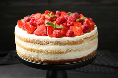 Tasty sponge cake with fresh berries and mint on dark gray table, closeup