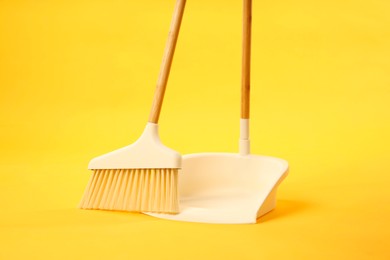 Photo of Cleaning broom and dustpan on yellow background