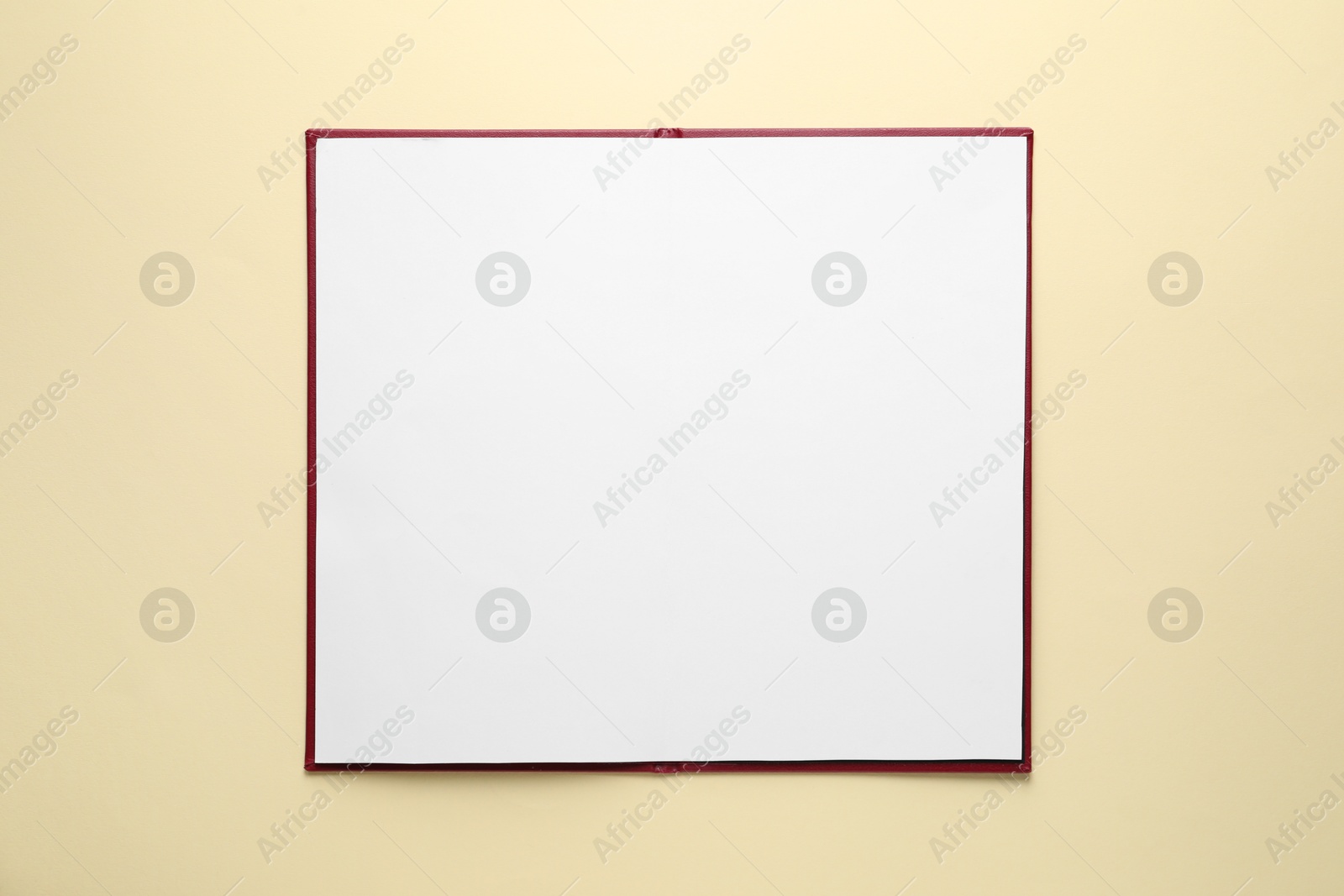 Photo of Open hardcover notebook with empty sheets on beige background, top view. Mockup for design