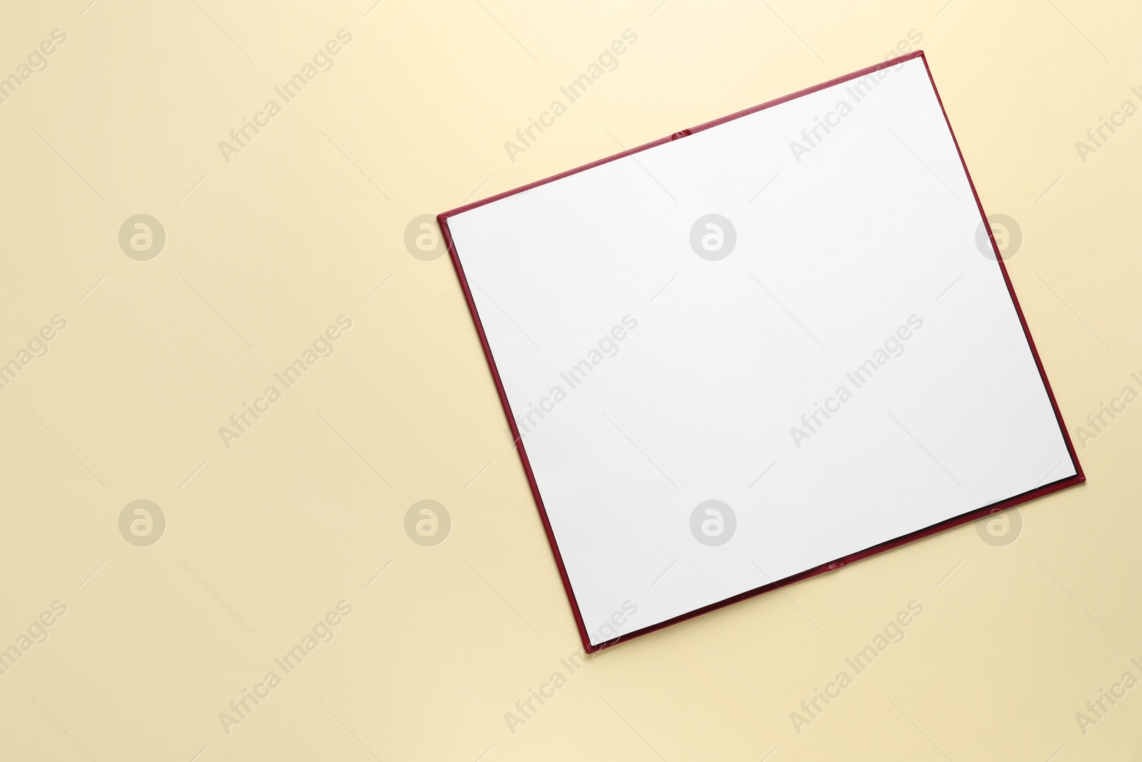 Photo of Open hardcover notebook with empty sheets on beige background, top view. Mockup for design