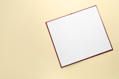 Photo of Open hardcover notebook with empty sheets on beige background, top view. Mockup for design