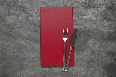 Photo of Hardcover menu and cutlery on grey textured table, top view