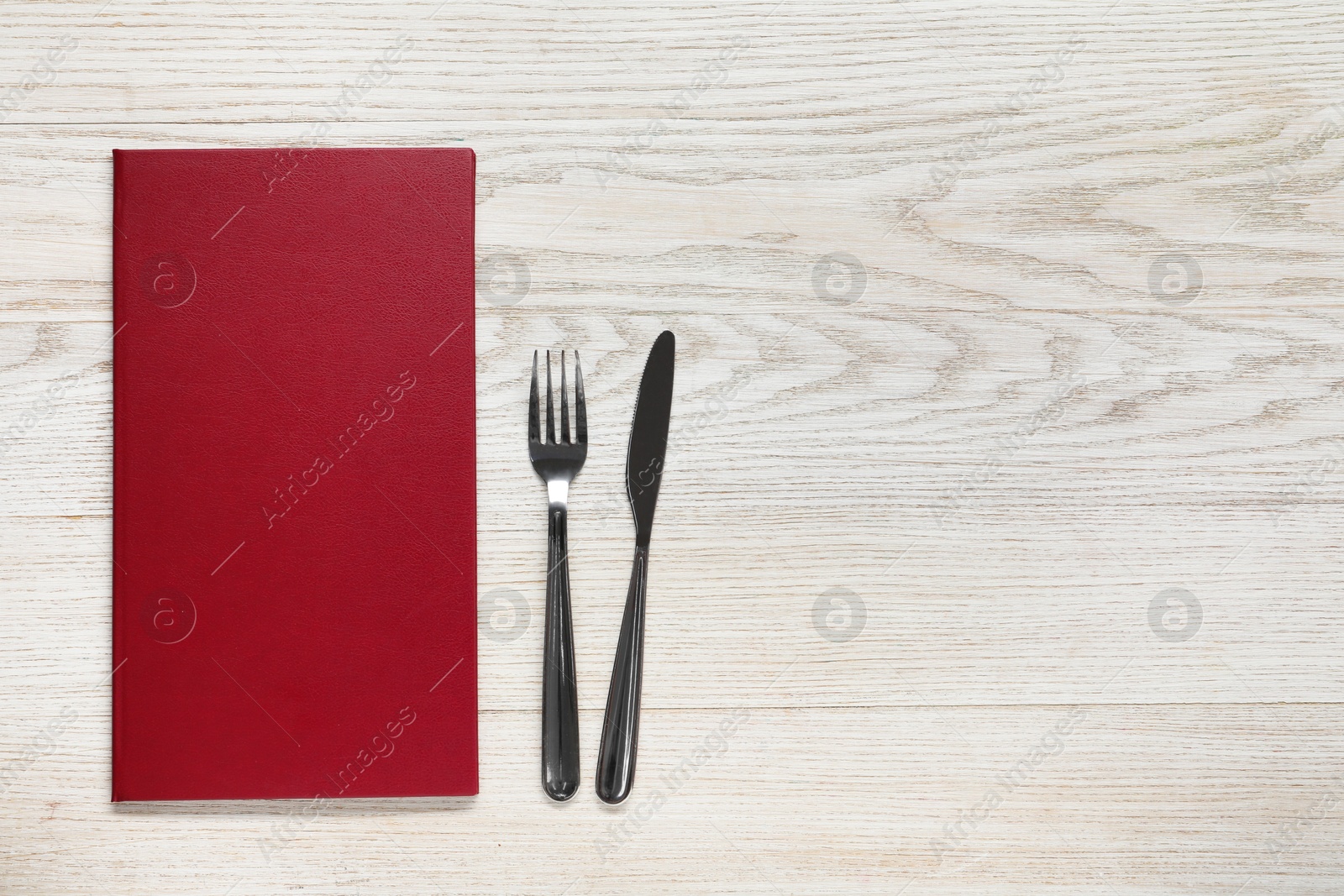 Photo of Hardcover menu and cutlery on white wooden table, flat lay. Space for text