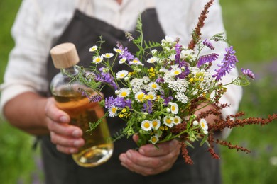 Senior woman with tincture and wildflowers outdoors, closeup