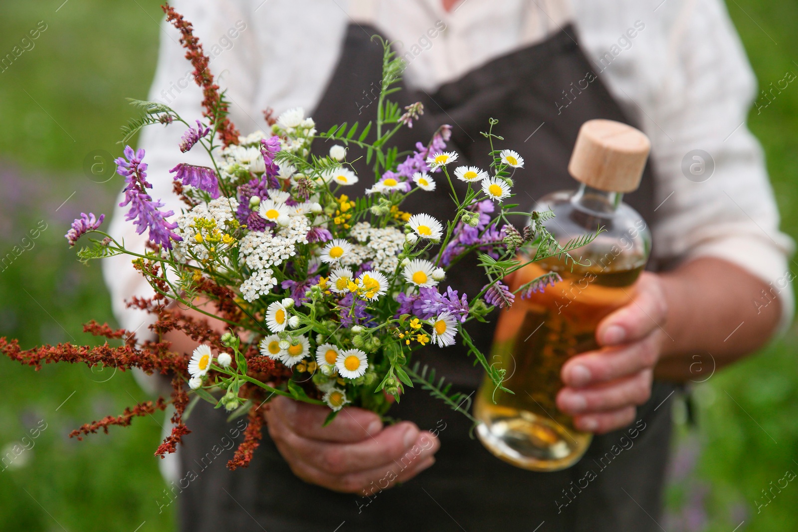 Photo of Senior woman with tincture and wildflowers outdoors, closeup