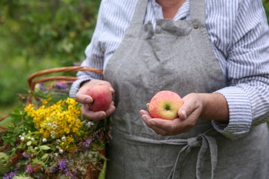 Photo of Senior woman with apples and wildflowers outdoors, closeup