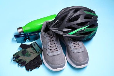 Bicycle helmet, sneakers, thermo bottle, fingerless gloves and goggles on light blue background