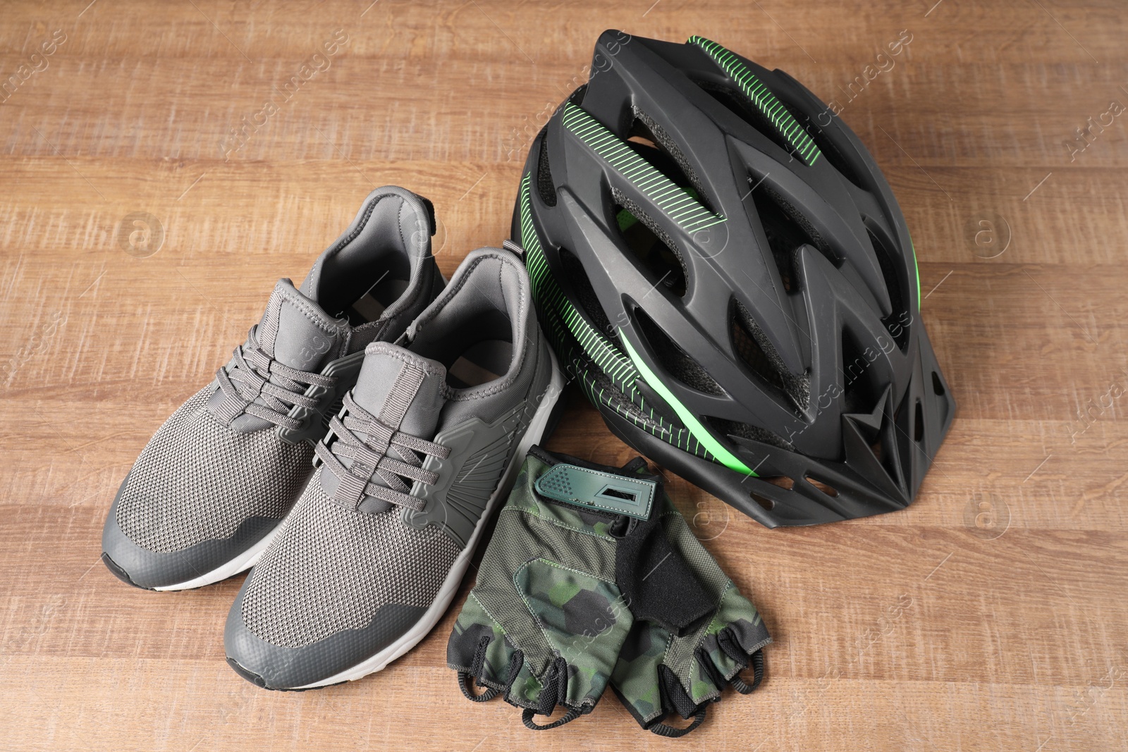 Photo of Bicycle helmet, sneakers and fingerless gloves on wooden background