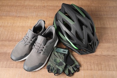 Bicycle helmet, sneakers and fingerless gloves on wooden background