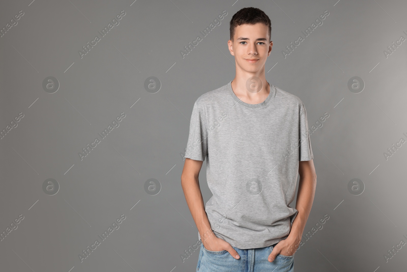 Photo of Teenage boy wearing t-shirt on grey background, space for text