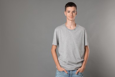 Photo of Teenage boy wearing t-shirt on grey background, space for text