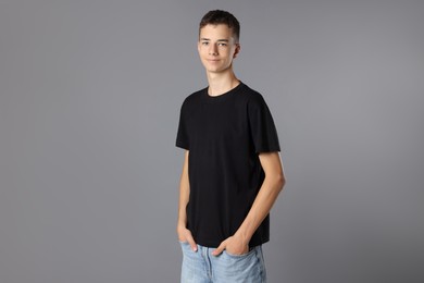 Teenage boy wearing black t-shirt on grey background