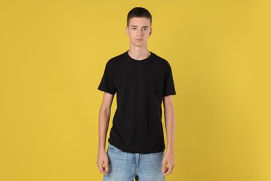 Teenage boy wearing black t-shirt on yellow background