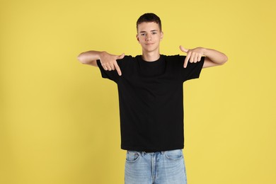 Teenage boy wearing black t-shirt on yellow background