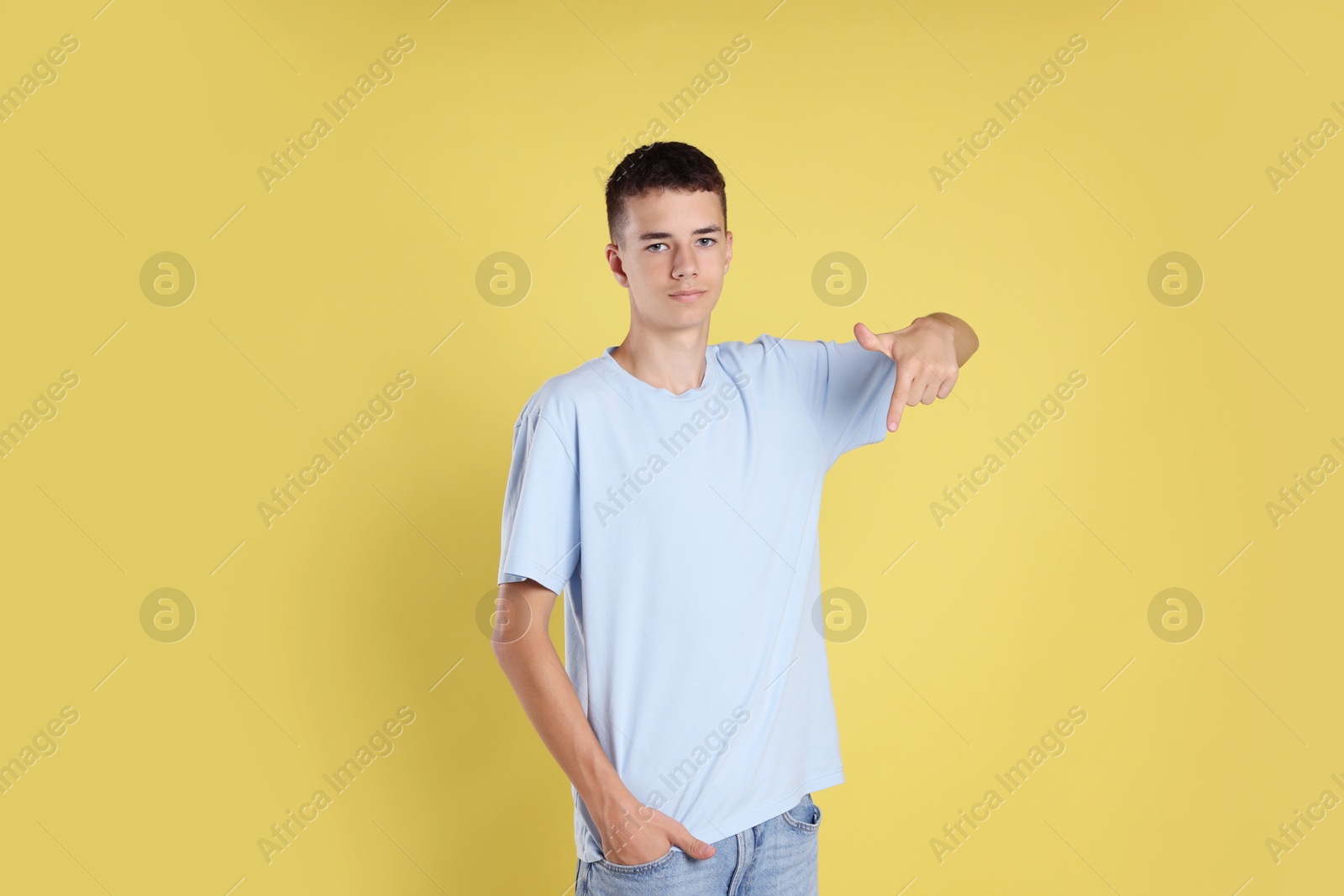 Photo of Teenage boy wearing light blue t-shirt on yellow background