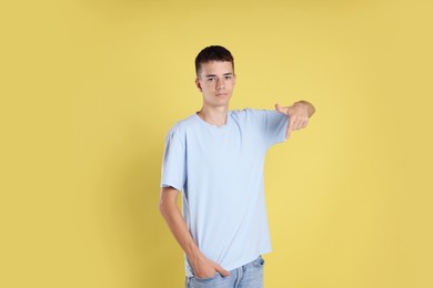 Photo of Teenage boy wearing light blue t-shirt on yellow background