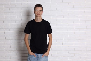 Photo of Teenage boy wearing black t-shirt near white brick wall, space for text