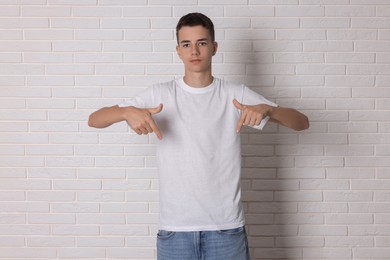 Photo of Teenage boy wearing t-shirt near white brick wall