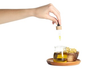 Photo of Woman dripping tincture from pipette into glass jar on white background, closeup