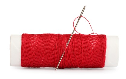 Photo of Spool of red sewing thread with needle isolated on white