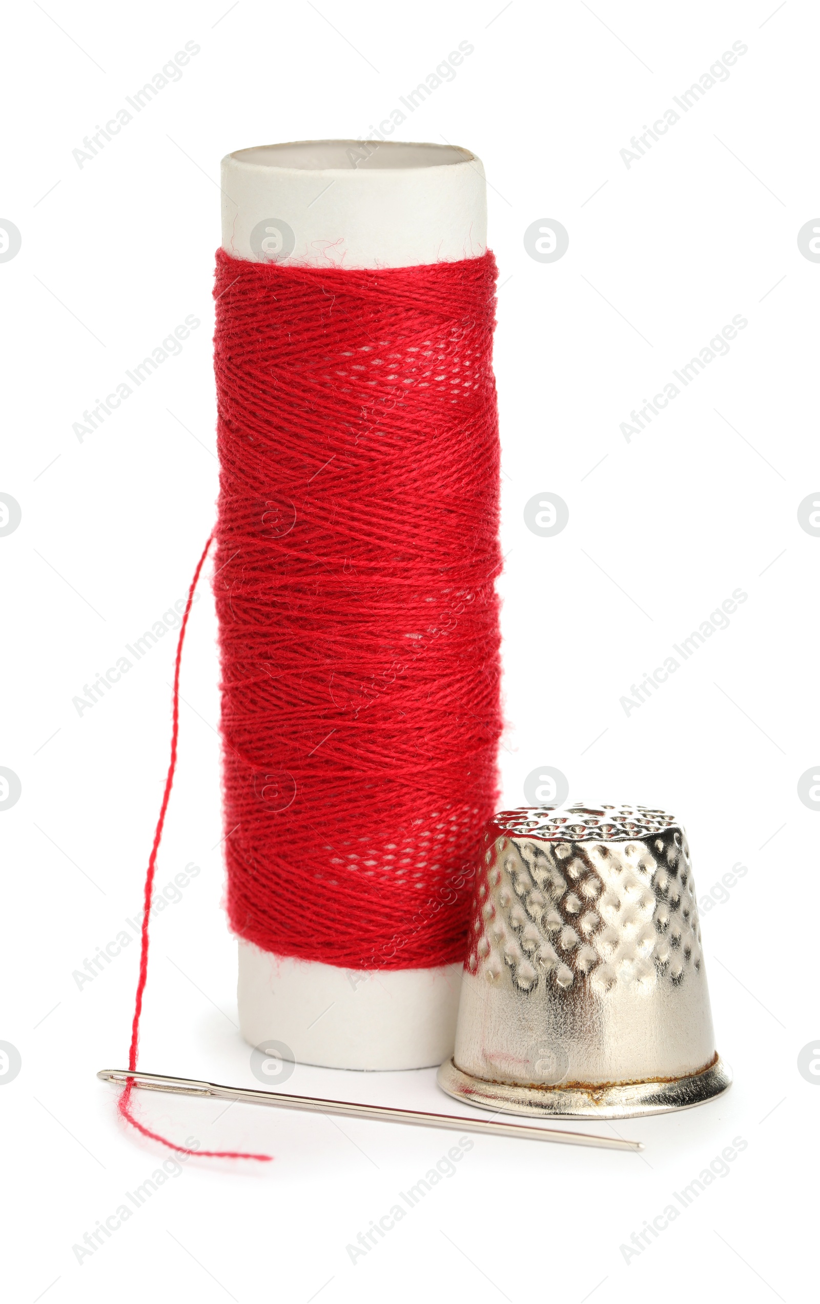 Photo of Thimble and needle with red sewing thread isolated on white