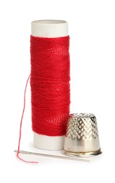 Photo of Thimble and needle with red sewing thread isolated on white