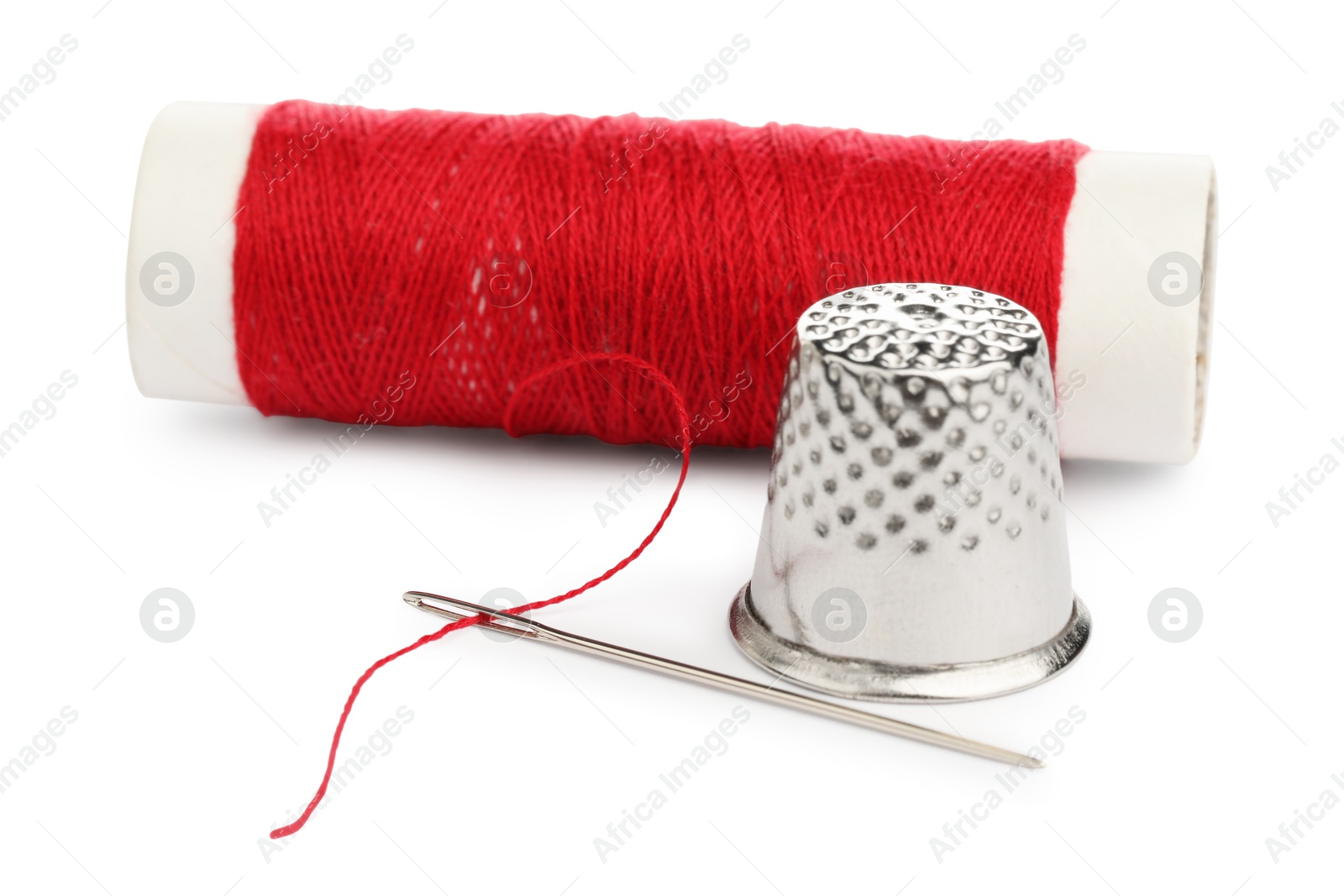 Photo of Thimble and needle with red sewing thread isolated on white, closeup