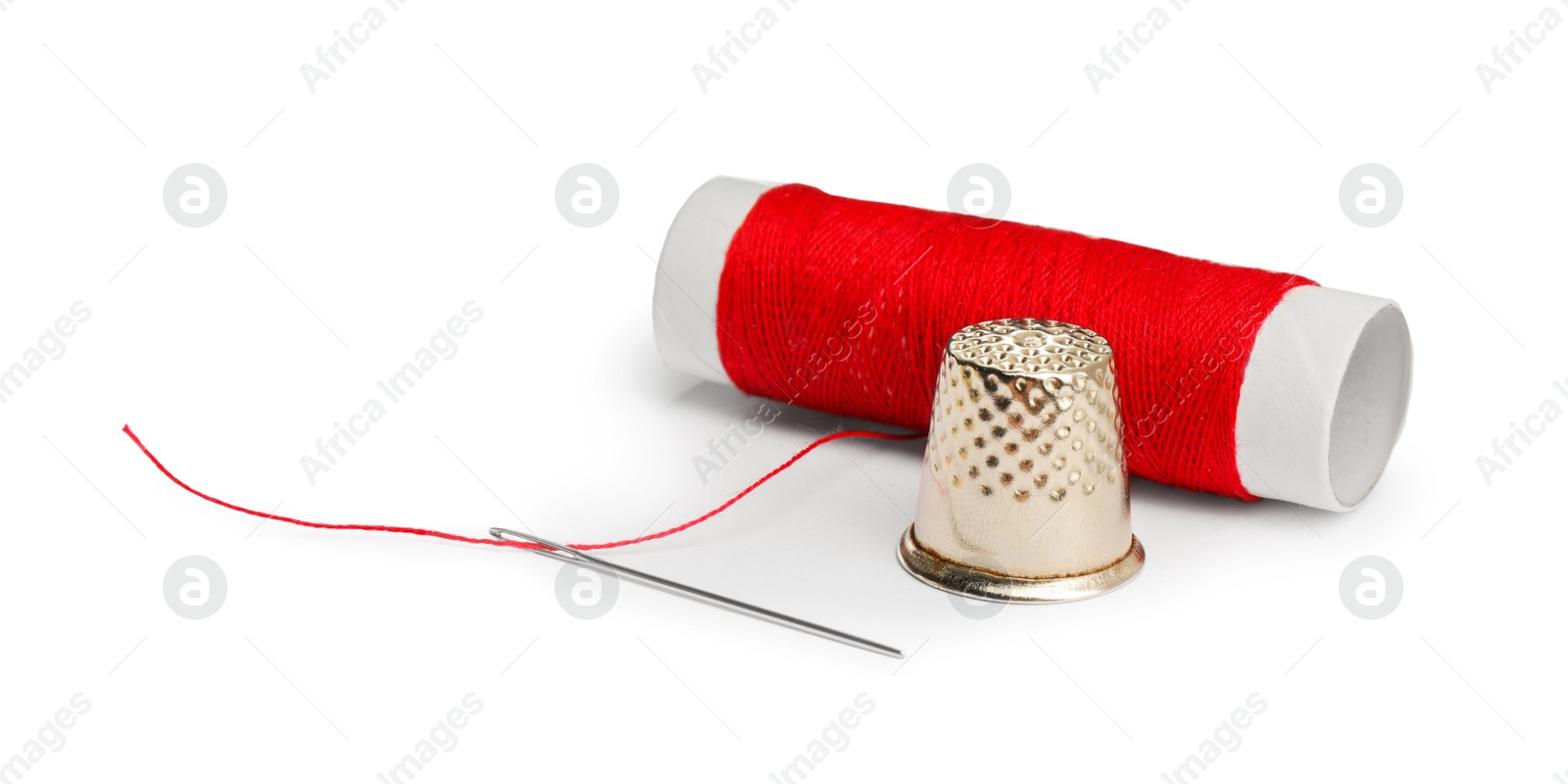 Photo of Thimble and needle with red sewing thread isolated on white