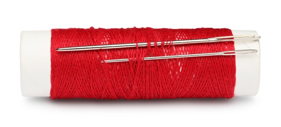 Photo of Spool of red sewing thread with needles isolated on white