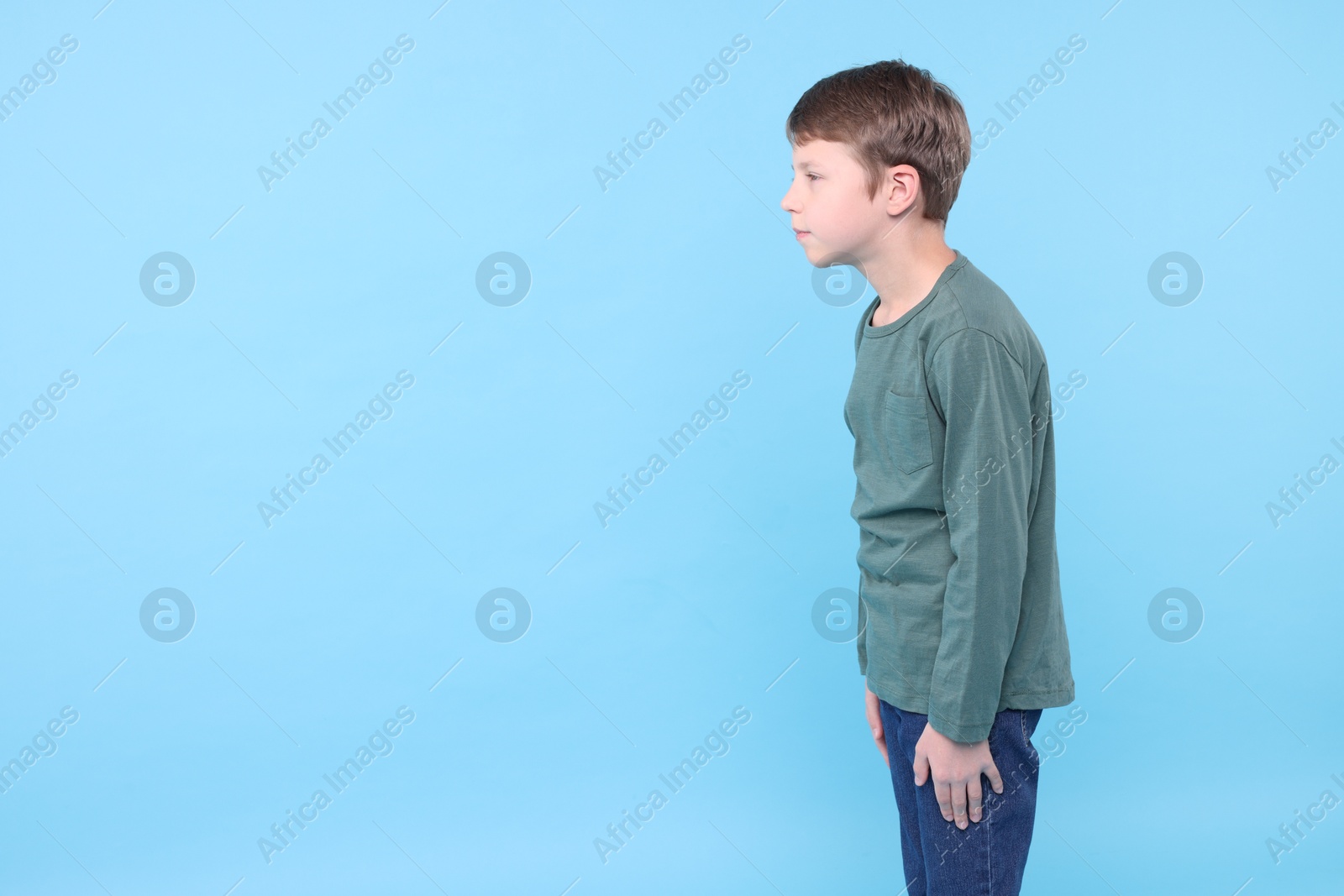 Photo of Boy with incorrect posture on light blue background