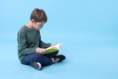 Photo of Boy with incorrect posture reading book on light blue background