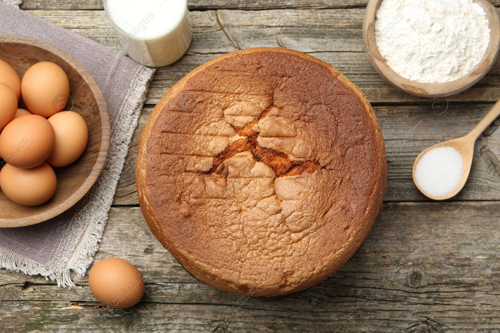 Photo of Tasty sponge cake and ingredients on wooden table, flat lay