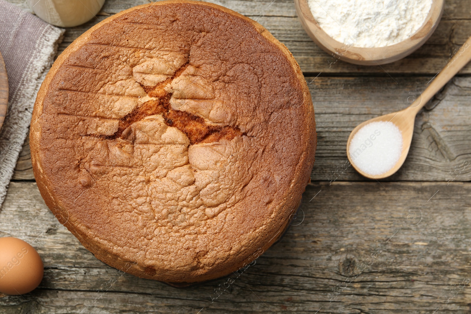 Photo of Tasty sponge cake and ingredients on wooden table, flat lay