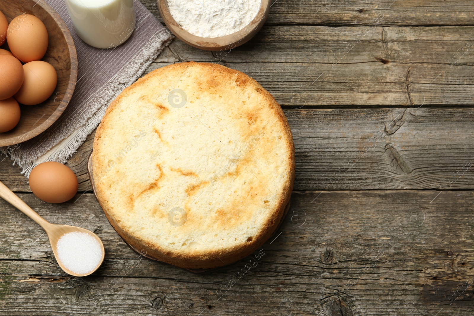 Photo of Tasty sponge cake and ingredients on wooden table, flat lay. Space for text