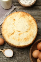 Photo of Tasty sponge cake and ingredients on wooden table, flat lay