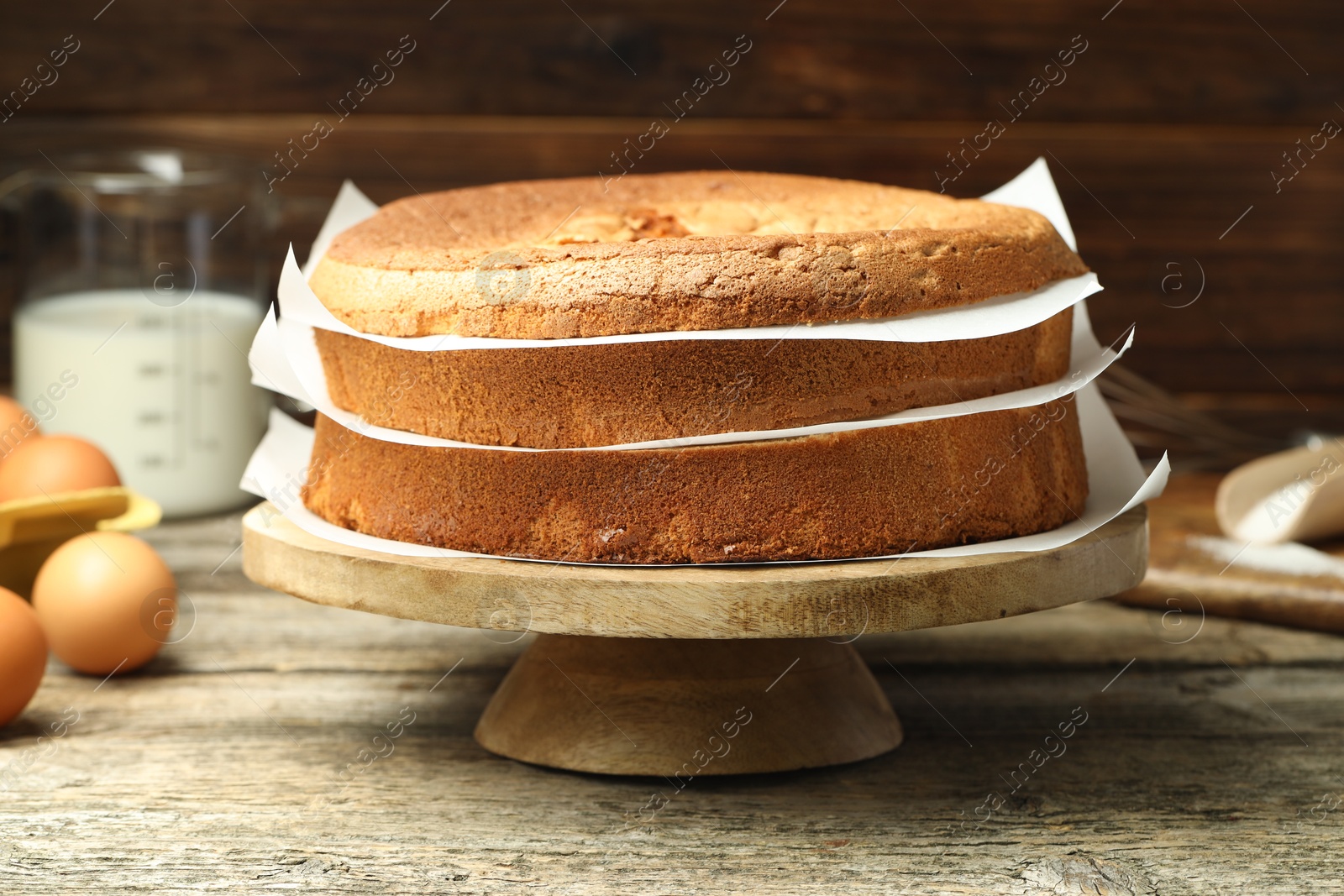 Photo of Tasty cut sponge cake and ingredients on wooden table