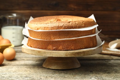 Photo of Tasty cut sponge cake and ingredients on wooden table